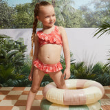Girl wearing raspberry hibiscus kids bikini set at the pool with inflatable float.