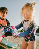 Two kids on dock wearing Blue Rose long sleeve one-piece rashguard and matching swim outfits