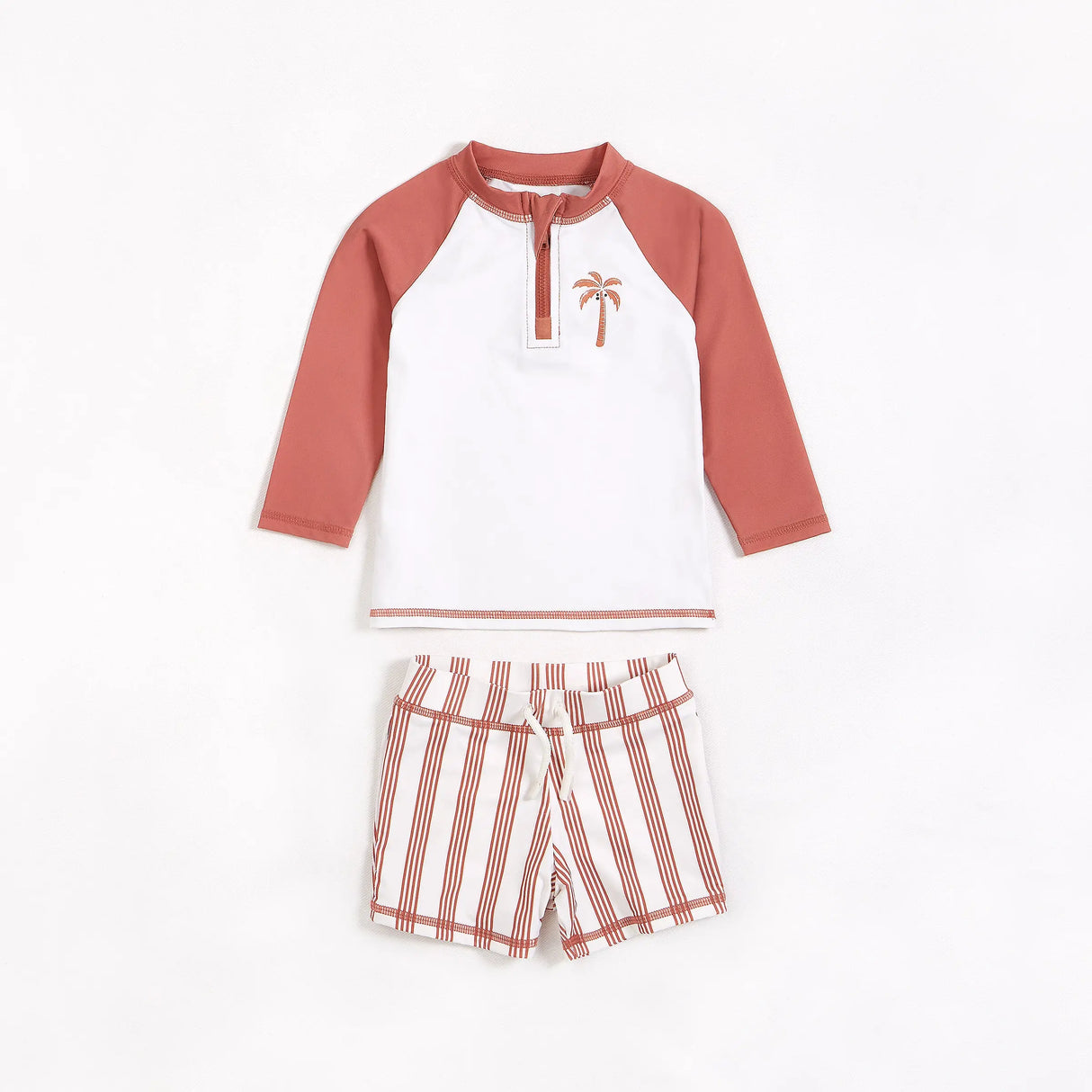 Red and white palm tree rashguard and striped swim shorts set for baby boy laid flat.
