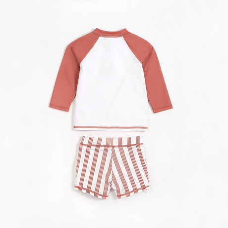 Palm tree raglan rashguard with matching striped swim shorts in red and white on neutral background.
