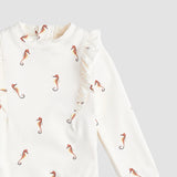Closeup of Miles The Label girls seahorse swimsuit showing Creme fabric, frilly shoulder trim, and stretch material.