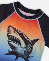 Close-up of shark graphic and neckline on blue/orange gradient rashguard top for boys