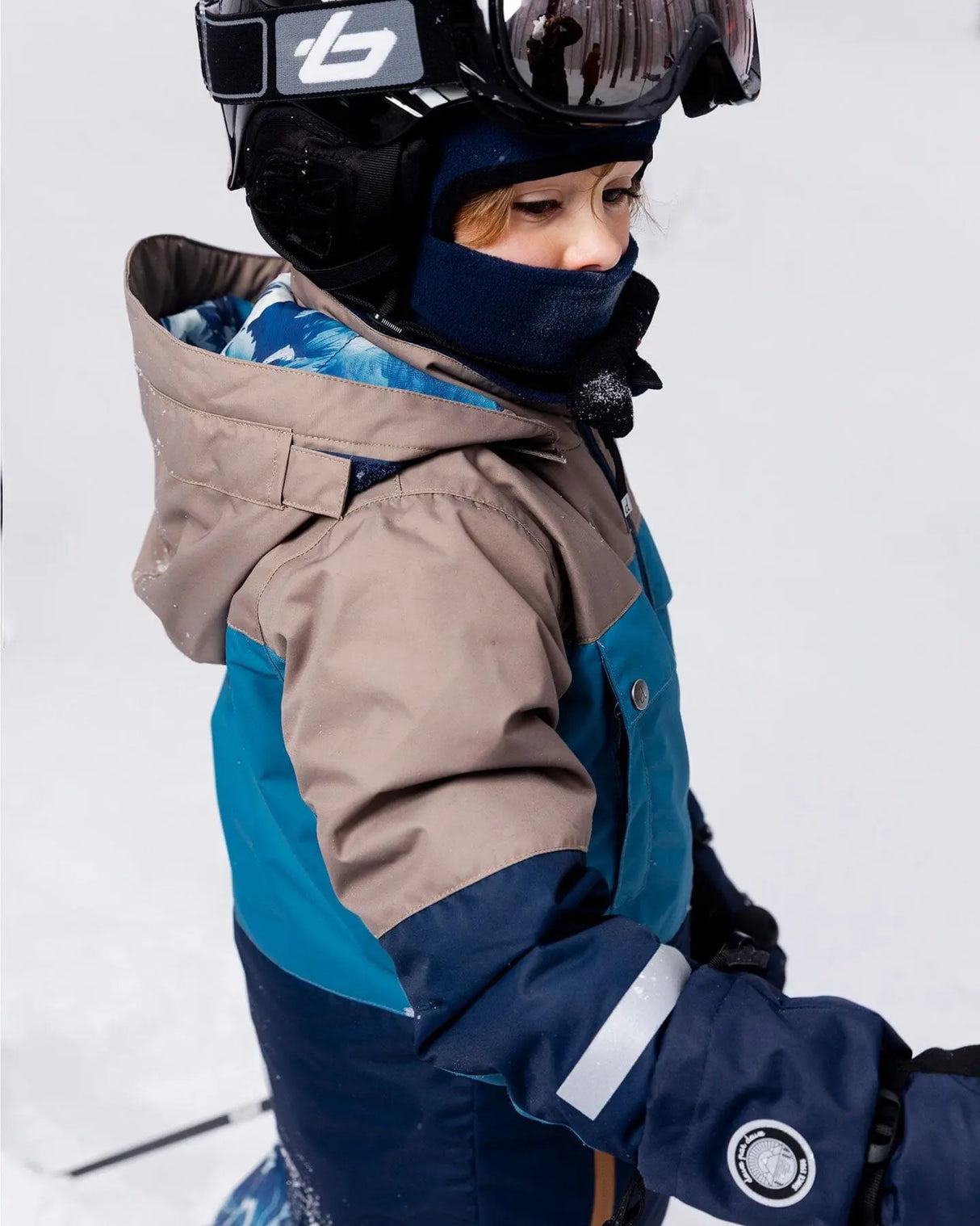 Side view of Teknik snowsuit with helmet-friendly hood and waterproof zippers