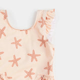 Close-up of rose starfish print and ruffled hip detail on Petit Lem baby girl swimsuit