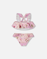 Detail shot of ruffled straps and floral print on purple girl two-piece swimsuit