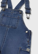 Closeup of Mayoral baby denim dungaree showing pocket detail, strap hardware, and cotton-blend fabric.