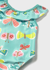 Closeup of Mayoral baby girl UPF swimsuit showing fish print, ruffle trim, and Aqua swim fabric.