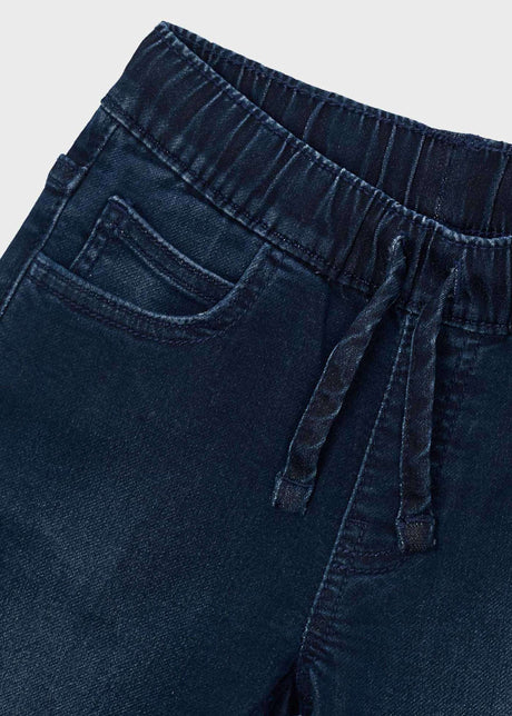 Close-up of elastic drawstring waist and front pocket on dark blue jeans