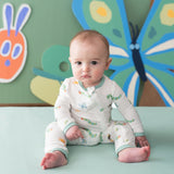 Baby sitting in Kyte Baby Caterpillar bamboo romper with playful wall art
