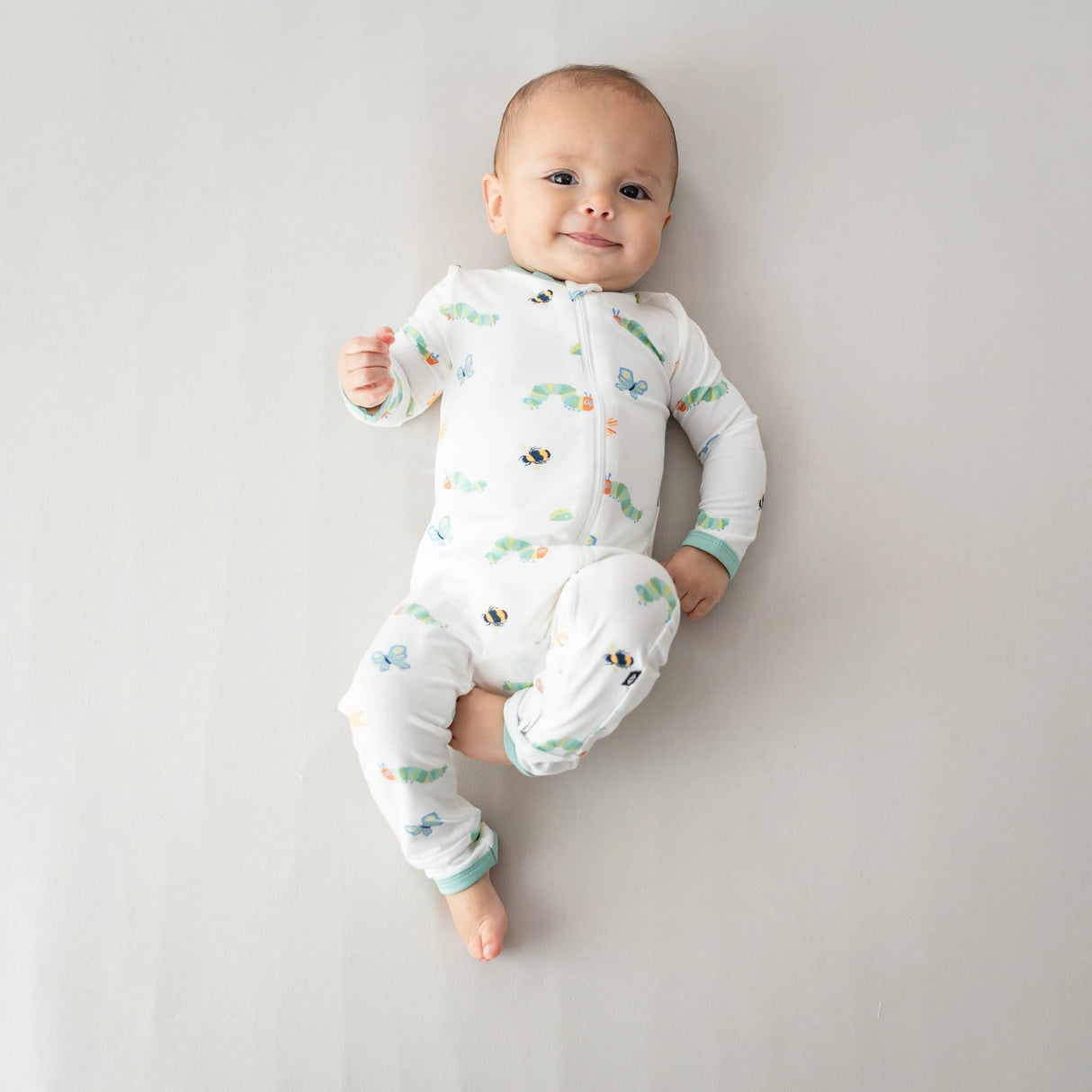 Baby lying down in Kyte Baby Caterpillar bamboo romper with dual zipper fit