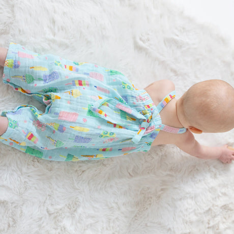 Baby lying in Angel Dear popsicle print muslin romper showing lightweight summer one-piece fit.